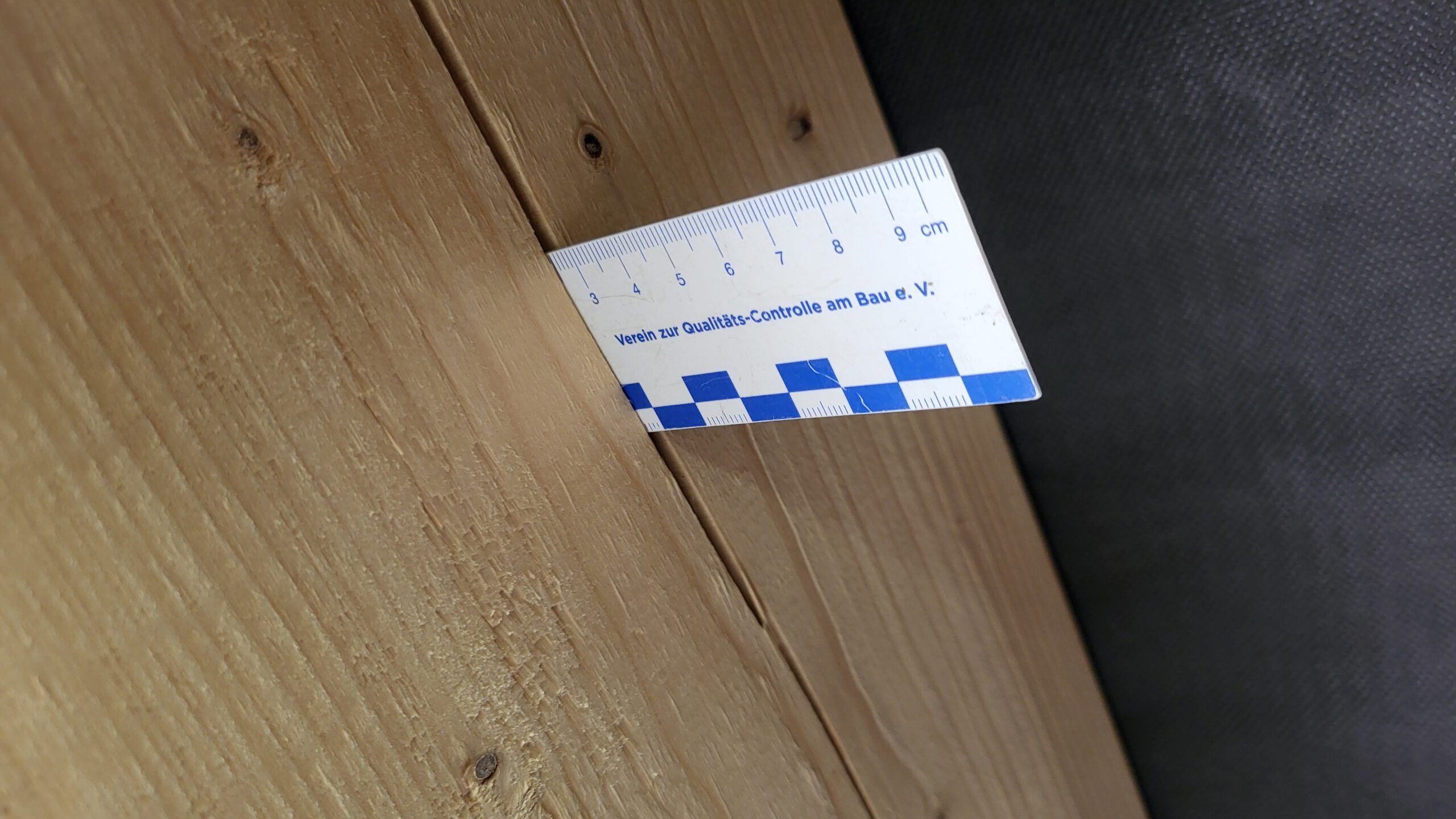 Rissbreitenmesser in einem gerissenen Holzbalken vom Dachstuhl
