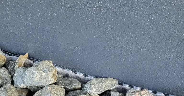 Fertig verlegter Sockelbereich mit Kies-Drainagestreifen: Am Übergang zwischen Sockelputz und Kies ist die helle Vliesschicht der dreilagigen Noppenbahn sichtbar